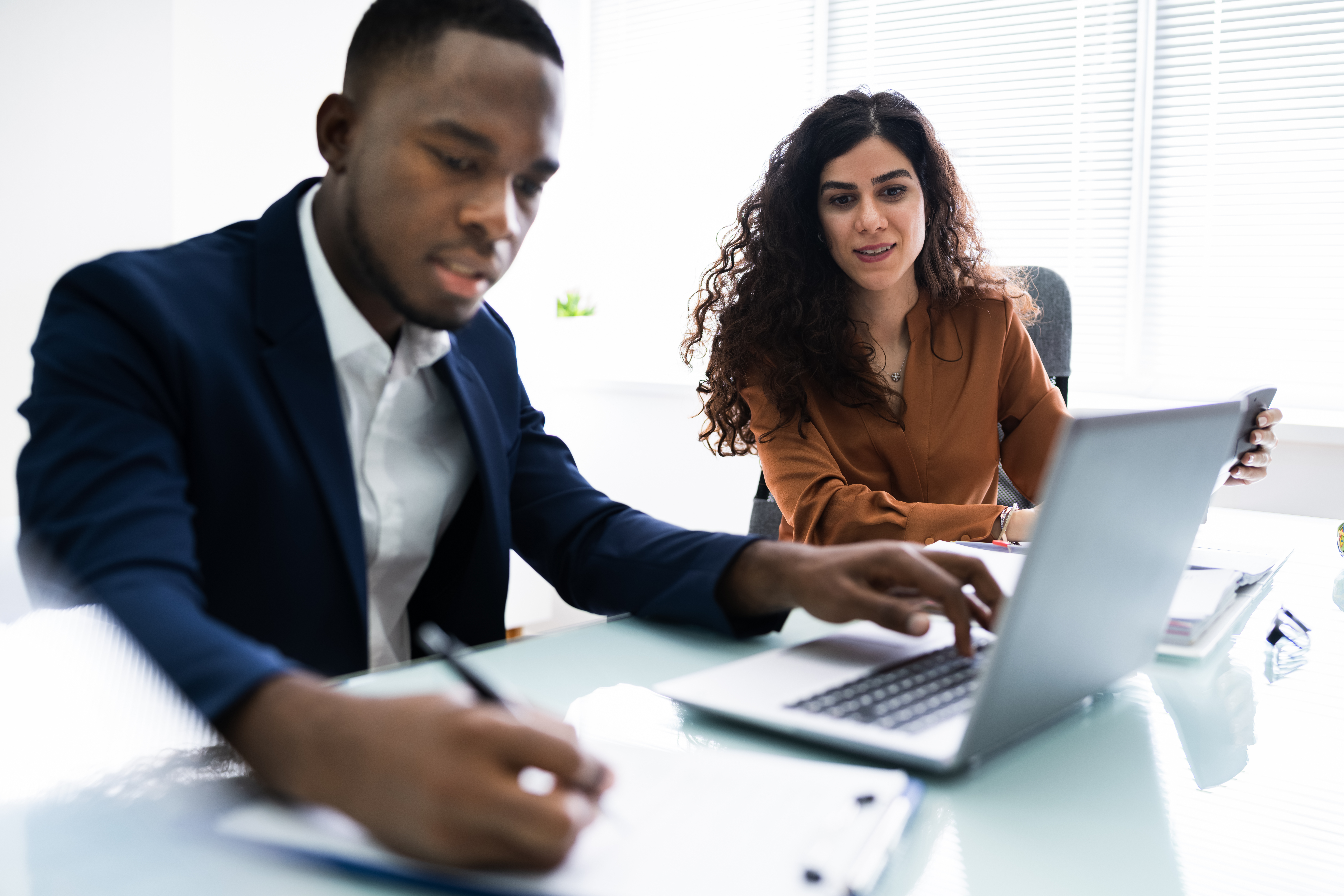 Two,Young,Businesspeople,Calculating,Invoice,With,Calculator