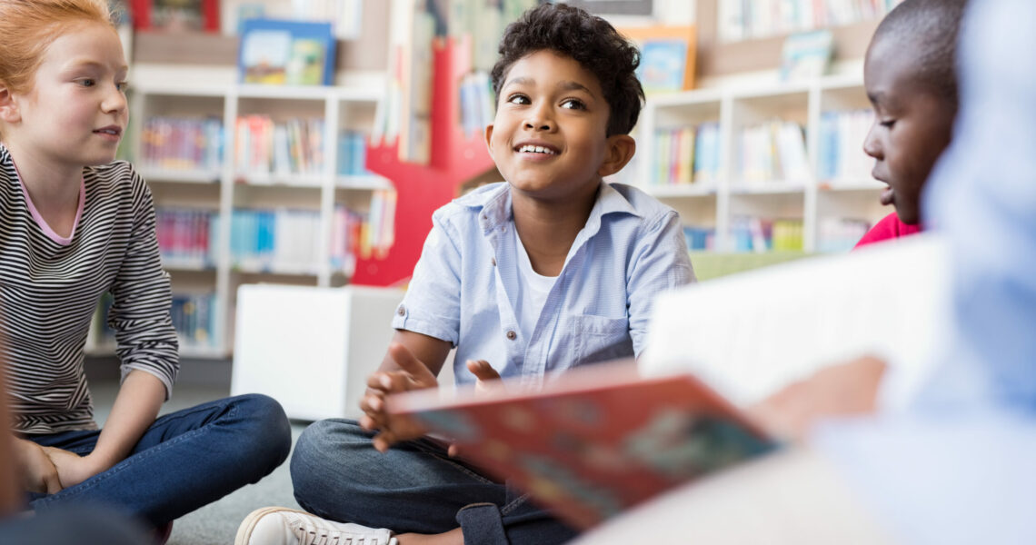 Smiling boy sitting on the floor amongst other children having a discussion