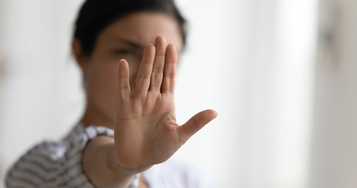Young woman holding out a flat hand to the camera to say stop