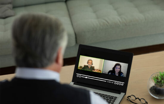 Man looking at laptop screen where a video conference is playing