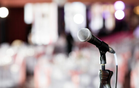 Microphone in front of a large bright room that is blurry in the background