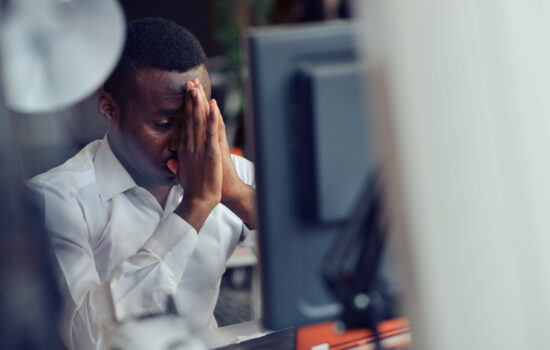 Tired or unhappy man sitting at his desk after a hard day