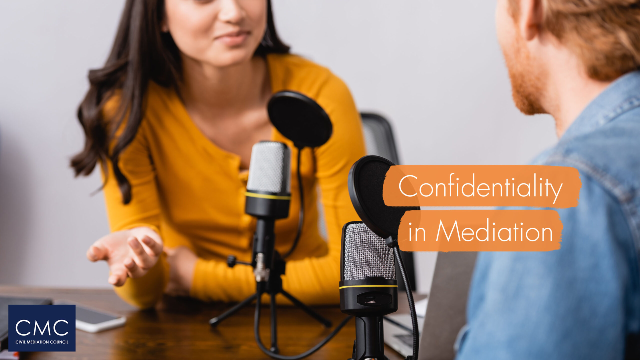 Man and woman recording a podcast sitting across from each other at a table