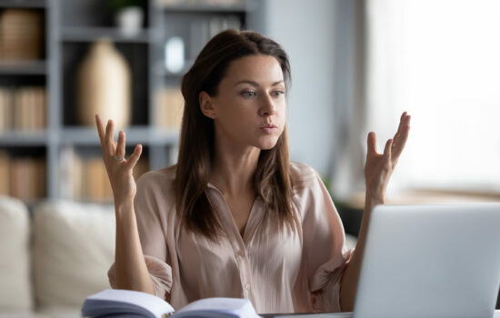 Woman at desk throwing up her hands in exasperation