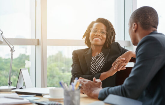 Smiling business woman in conversation sitting at a desk with a man