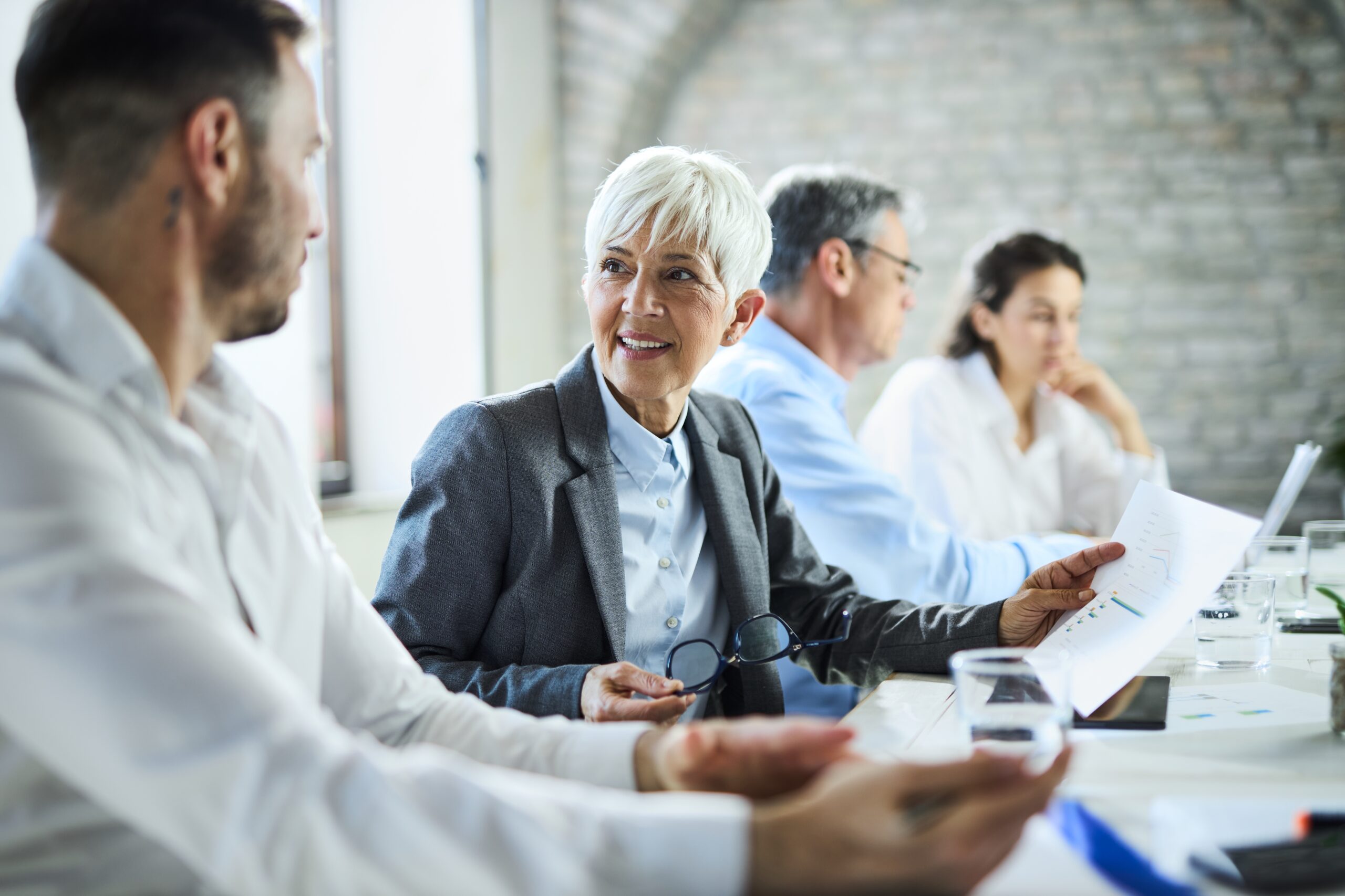 Happy,Senior,Businesswoman,Talking,About,Reports,With,Her,Colleague,On